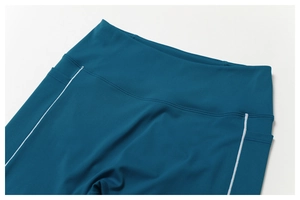 Detalle de mallas de yoga de talle alto con bolsillos laterales y costuras blancas en contraste