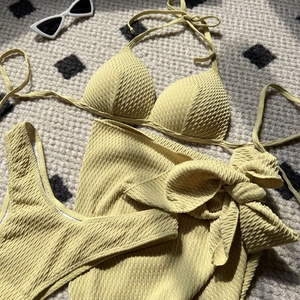 Detailed view of yellow textured three-piece bikini set with side-tie sarong