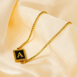 Macro view of gold plated chain and black enamel square pendant with letter A