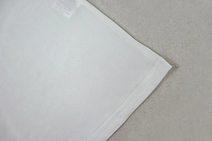Detailed close-up of double-needle stitching on the hem of a white cotton dress