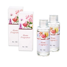 Detail van twee 50ml glazen huisparfumflessen met bloemendozen en heldere vloeistof