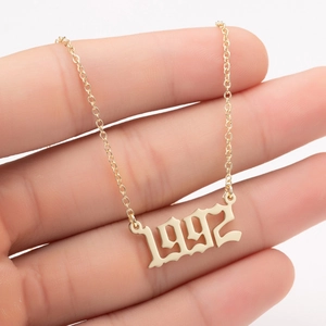 Macro detail of the 1992 gothic number pendant on a gold stainless steel chain necklace