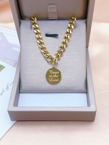 Makroaufnahme einer Goldkette mit Anhänger Trust in the Lord auf rosa Satin-Hintergrund