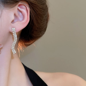 Macro view of long wavy earrings with sparkling crystals shown on a model