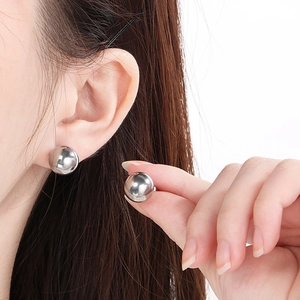 Macro shot of polished silver spherical stud earrings on a model showing the mirror finish