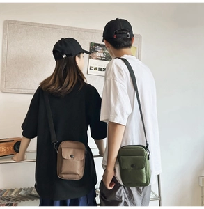 Detail view of khaki and olive canvas crossbody bags shown in a lifestyle couple setting