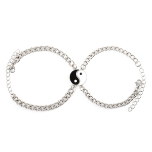 Close-up of Yin Yang Tai Chi charms on polished stainless steel Cuban link bracelets