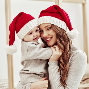 Matching red and white knitted Christmas pom-pom hats for mother and baby on models