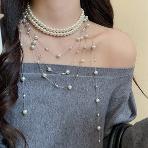 Close-up of layered faux pearl fringe necklace on model wearing grey knitwear