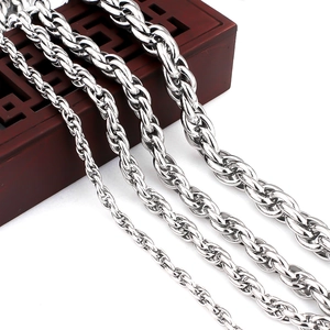 Detail of four silver twisted rope chains in varying widths on a dark wood box