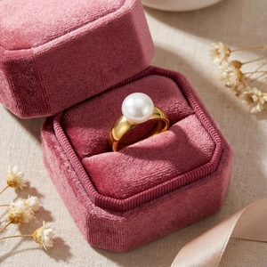 Close-up of a golden pearl ring presented in a pink velvet jewelry gift box