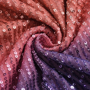 Macro shot of gradient sequin fabric with shimmering orange to purple holographic finish