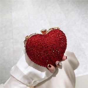 Luxury heart-shaped clutch bag with red crystals and gold metal frame held in hand