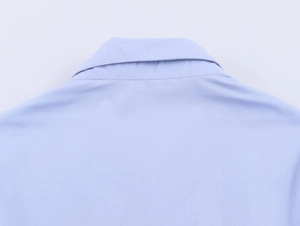 Macro view of light blue poplin shirt showing rear neckline and fine stitching texture