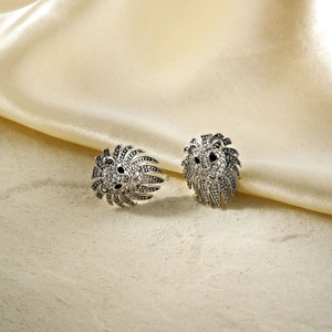 Boucles d'oreilles tête de lion argentées serties de zircons sur fond de sable fin