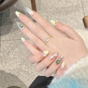 Hand-painted bow pearl press-on nails with green teardrop gems and almond shape finish