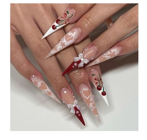 Close-up of stiletto nails with 3D bows, cherry art, and pearl details on pink base