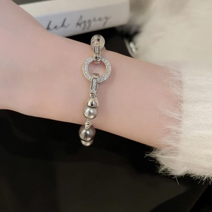 Detailansicht von Perlen- und Zirkon-Armband am Handgelenk mit glänzendem Metallfinish