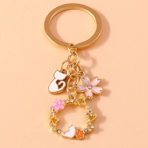 Close-up of golden cat and cherry blossom keychain with sparkling rhinestone heart wreath