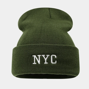Gros plan sur la maille serrée et la broderie blanche NYC sur un bonnet en tricot vert foncé