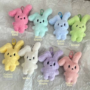 Flat lay of colorful plush rabbit keychains in eight pastel macaron shades on white paper