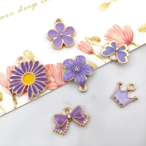 Close-up of purple enamel alloy pendants including daisies, butterflies and crowns