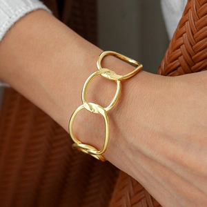 Macro detail of gold chunky irregular geometric chain link bracelet on woman's wrist
