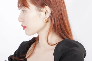 Close-up of model wearing gold-plated wide C-hoop earrings with white shell inlay