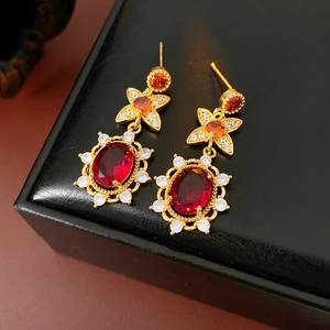Detailansicht goldener Vintage-Ohrringe mit roten Zirkonia und eleganten Schleifendetails