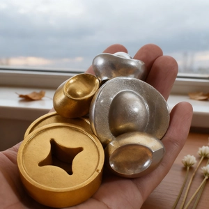 Detailed view of handmade golden sycee and coin resin charms held in hand for scale