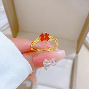 Bague trèfle dorée ajustable avec cœurs rouges et anneau tressé portée à la main