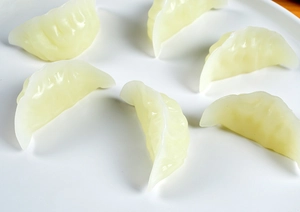 Detailed view of hyper-realistic dumpling miniatures on a white ceramic plate