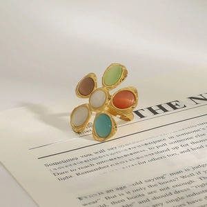 Détail d'une bague fleur dorée avec pétales d'opale colorés sur une page de livre