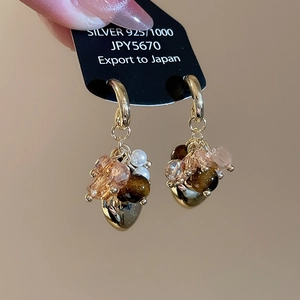 Macro detail of tiger eye stone tassel earrings with 925 silver needles and gold rings