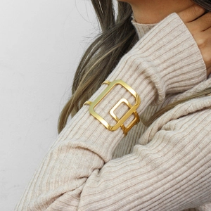Detailed view of an 18K gold plated oversized geometric open cuff bracelet on a sleeve