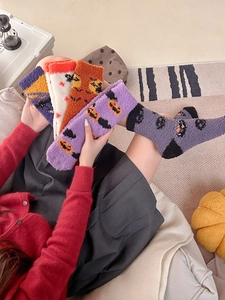 Close-up of fuzzy Halloween crew socks featuring colorful pumpkin and ghost patterns