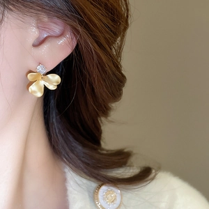 Close-up of elegant gold flower stud earrings with zircon stone on model side profile