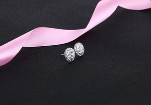 Close-up of sparkling S925 silver oval stud earrings with pavé crystals on black background