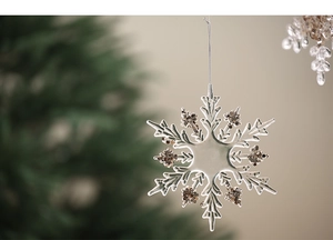 Detailed view of a transparent snowflake ornament with bronze glitter on a Christmas tree