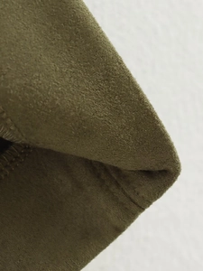 Close-up of olive green suede fabric texture and neat stitching on the pencil skirt