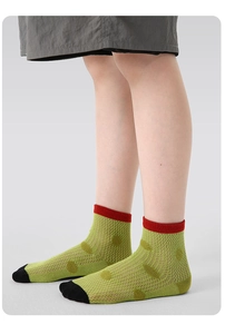 Detail of breathable mesh kids' socks featuring retro green polka dots and red cuffs