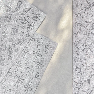 Detailed view of silver glitter nail art stickers featuring mermaid and cross patterns