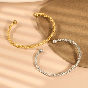Detail von zwei gedrehten Armreifen in Gold und Silber mit kugelförmigen Endstücken