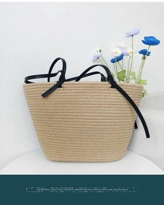 Detailed texture of natural beige woven tote with stylish black knotted shoulder straps