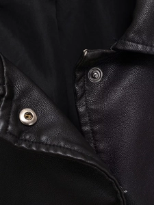 Gros plan sur la texture du cuir noir et les boutons-pression métalliques du blouson