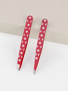 Close-up of red polka dot stainless steel eyebrow tweezers and precision pointed tip tool