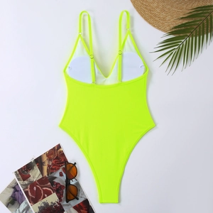 Flat lay of neon green one-piece swimsuit with beach accessories and sunglasses