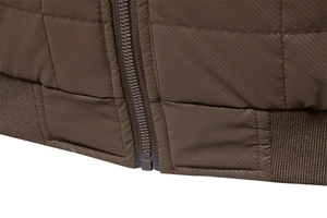 Detail of brown quilted jacket featuring a durable zipper and elastic ribbed hem