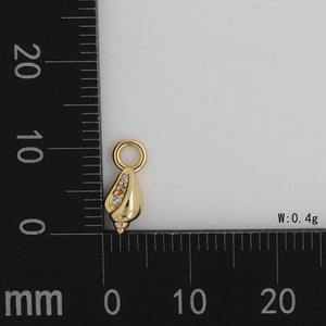 Macro detail of a 15mm gold-plated shell pendant with cubic zirconia and a scale ruler