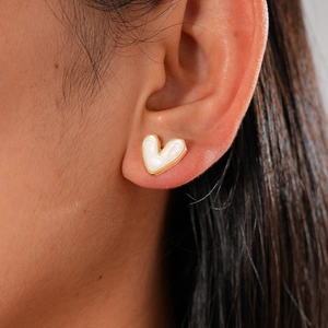 Minimalist cream heart stud earring set with golden edges worn by a model in a close-up view